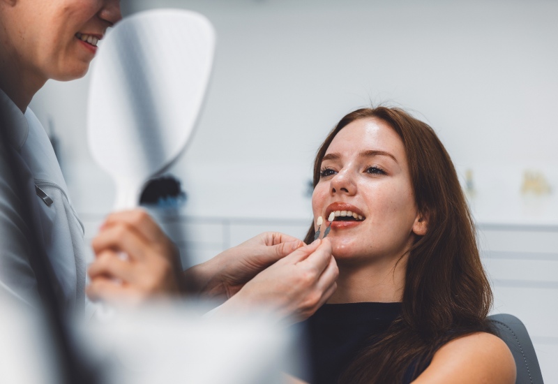 A dental professional is fitting a dental veneer on a smiling patient in Oklahoma City