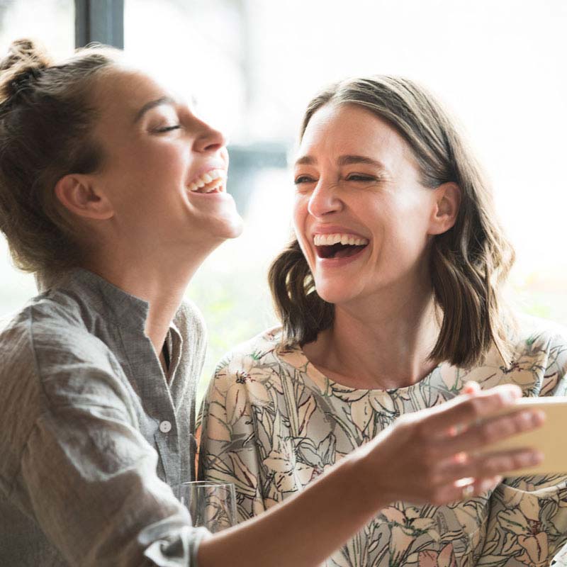 Two sisters smiling at each other after their dental procedure in Greater Oklahoma City.