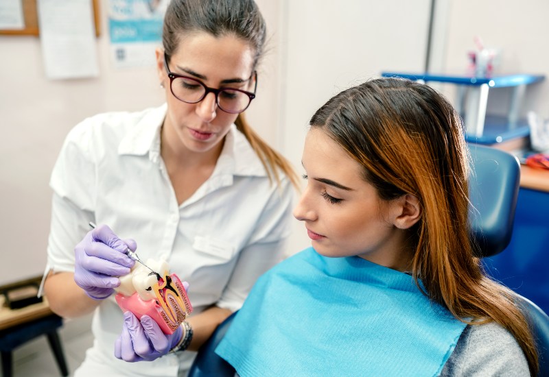 A dental professional is fitting a dental veneer on a smiling patient in Oklahoma City